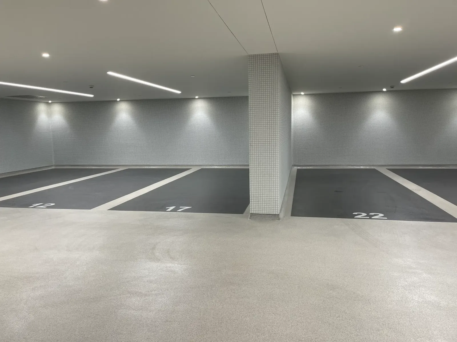 Parking de bureaux rénové avec sol en résine gris foncé, marquage blanc et places numérotées