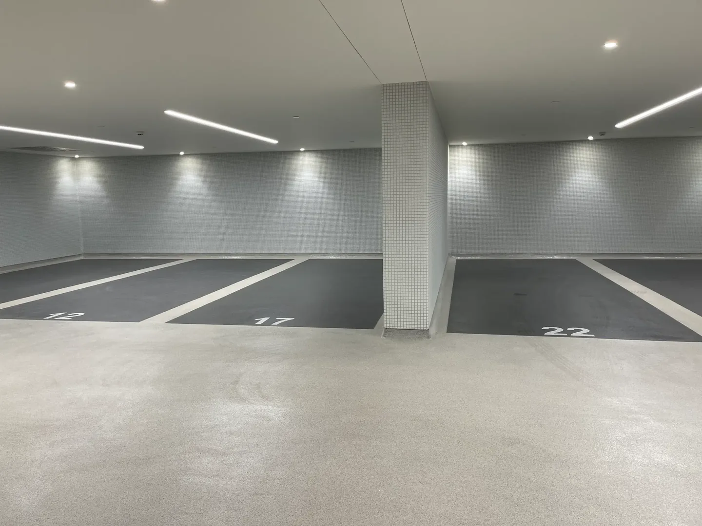 Places de stationnement gris foncé délimitées par des bandes claires et numérotées
