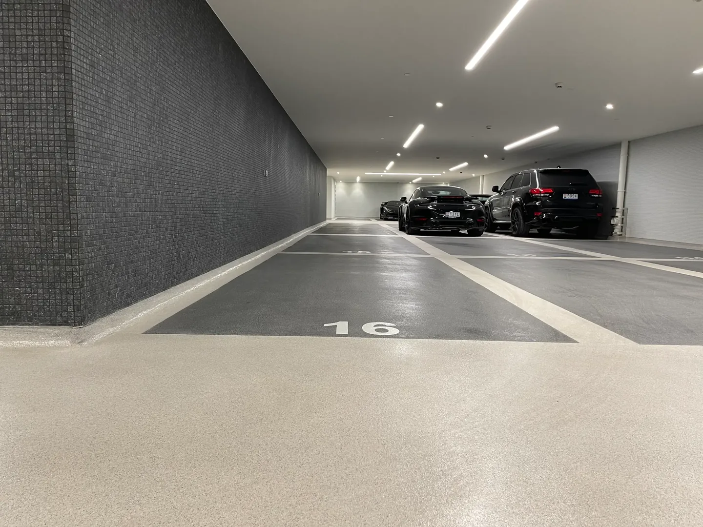 Parking couvert avec places numérotées, sol gris et véhicules stationnés