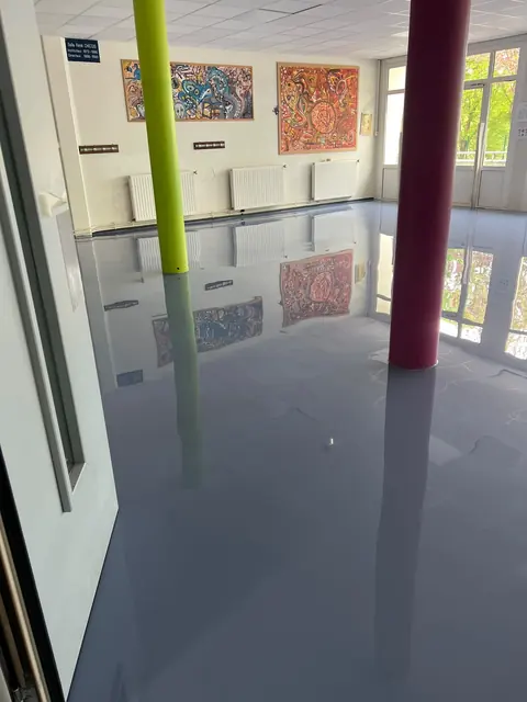Espace d’accueil avec sol en résine gris foncé et colonnes colorées