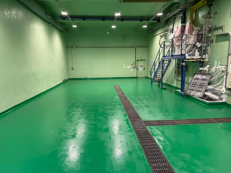 Vue d’ensemble du sol vert en résine et des caniveaux dans l’atelier agroalimentaire.